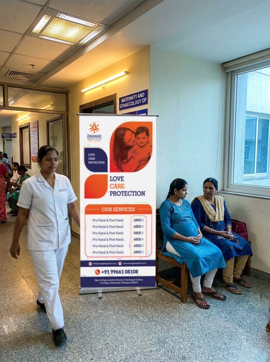 Orange Hospitals mother and child care standee outside the maternity and gynaecology OP with a pregnant woman waiting, photo mockup
