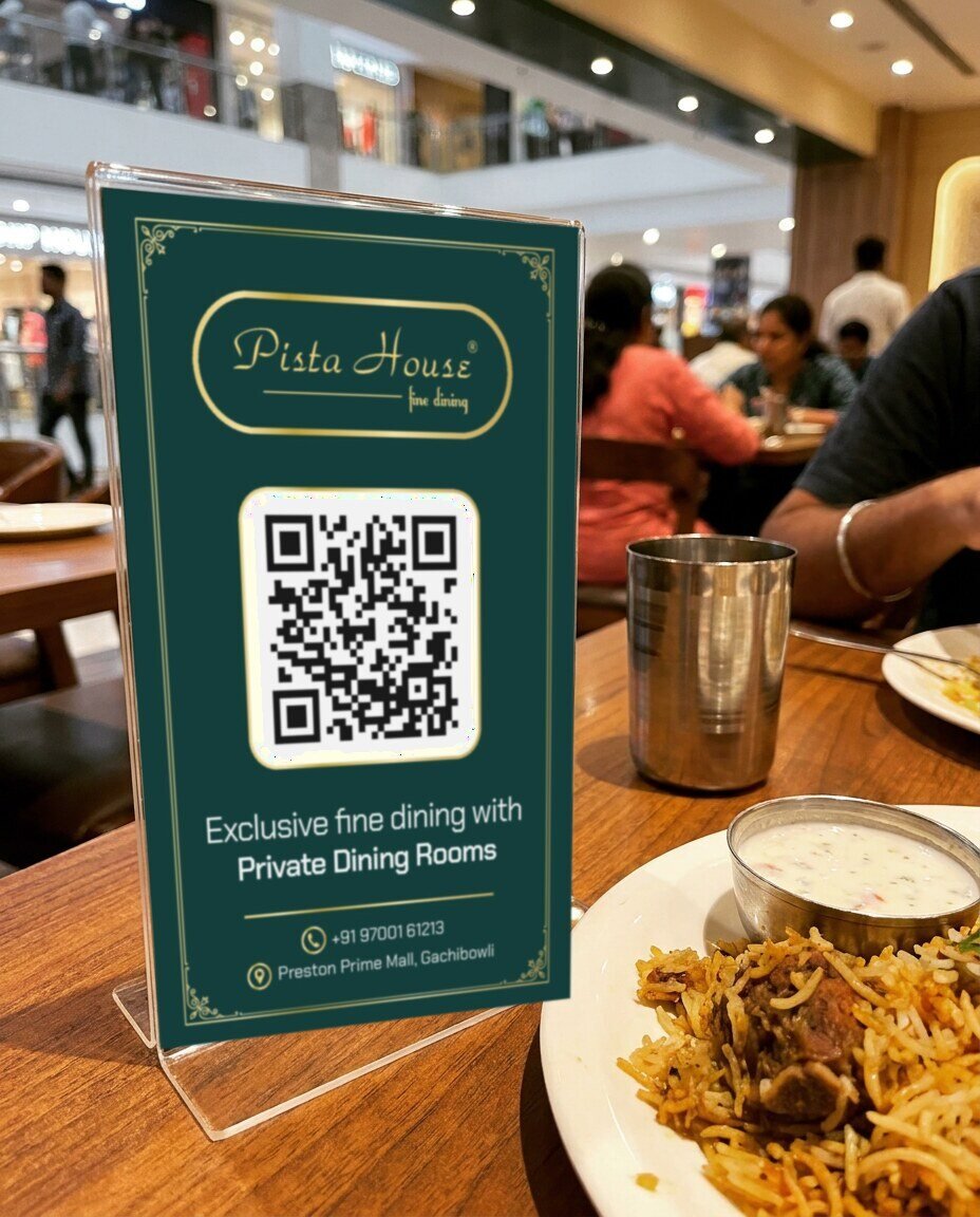 Pista House QR tent card on a restaurant table next to biryani and raita at Preston Prime Mall, photo mockup